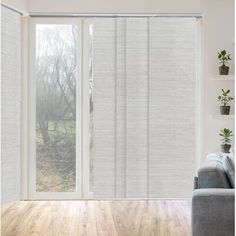 a living room with sliding glass doors and wood flooring that has white blinds on the windows