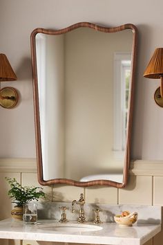 a bathroom sink with a mirror above it and two lamps on the wall next to it