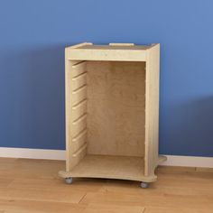 a small wooden shelf on wheels in a room with blue walls and hardwood flooring