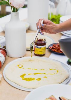 a person is making food on a table with flowers in a vase and sauces