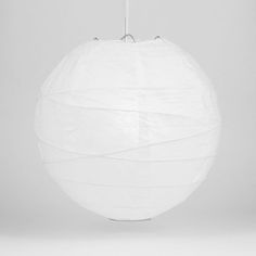 a large white paper lantern hanging from a metal hook on a gray background with the light turned off