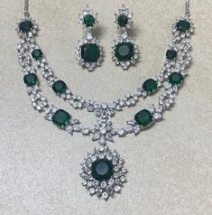 Emerald Necklace Set inspired by Sabyasachi Feturing semi precious green stone in white rhodium plating. Ideal to pair with your indi western sarees and gowns. Perfect gift for her. *𝐏𝐑𝐎𝐃𝐔𝐂𝐓 𝐃𝐄𝐓𝐀𝐈𝐋* * 𝐌𝐚𝐭𝐞𝐫𝐢𝐚𝐥: Brass * 𝐏𝐥𝐚𝐭𝐢𝐧𝐠: White Rhodium Plated * 𝐒𝐭𝐨𝐧𝐞: AAA-quality CZ Diamond & Emerald. *𝐃𝐈𝐌𝐄𝐍𝐒𝐈𝐎𝐍𝐒* *𝐍𝐞𝐜𝐤𝐥𝐚𝐜𝐞* * 𝐖𝐞𝐢𝐠𝐡𝐭: 56 gm * 𝐃𝐫𝐨𝐩 𝐋𝐞𝐧𝐠𝐭𝐡: 6.1 cm * 𝐖𝐢𝐝𝐭𝐡: 1.1 cm *𝐏𝐞𝐧𝐝𝐚𝐧𝐭* * 𝐋𝐞𝐧𝐠𝐭𝐡: 1.3 cm * 𝐖𝐢𝐝𝐭𝐡: 1.2 Luxury Gift Chandbali Emerald Necklace, Luxury Stone Work Necklaces For Eid, Luxury Gift Emerald Chandbali Necklace, Luxury Emerald Temple Necklace For Receptions, Luxury Green Emerald Necklace With Meenakari, Dazzling Green Emerald Necklace For Formal Occasions, Dazzling Green Emerald Necklace, Round Green Emerald Necklace With Jewels, Fine Jewelry Emerald Necklace