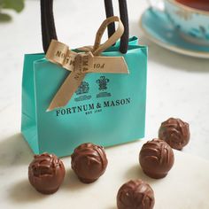 four chocolate candies sitting in front of a teal bag with the word fortnum & mason on it