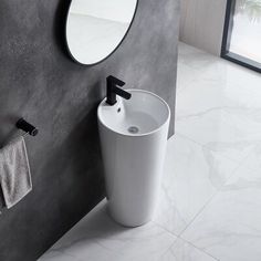 a white sink sitting next to a mirror in a bathroom under a round shaped mirror