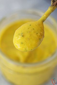 a spoon full of yellow sauce on top of a table