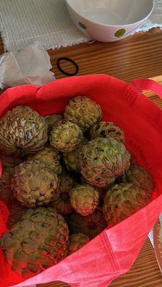 a red bag filled with pineapples on top of a wooden table