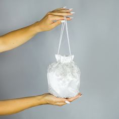 a woman's hand holding a white bag with lace on it