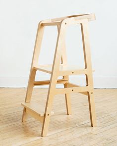 a wooden step stool sitting on top of a hard wood floor next to a white wall