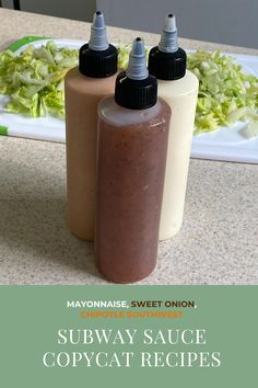 two bottles of sauce sitting on top of a counter next to a plate with lettuce