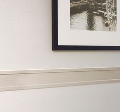 a black and white photo hanging on the wall next to a water way with a bridge in the background