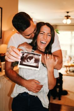 a man and woman hugging each other while holding an old photo in front of them