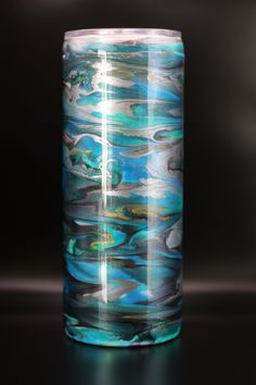 a glass vase sitting on top of a black table covered in blue and green liquid