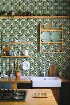 a kitchen with green and yellow wallpaper, white sink and wooden countertop area