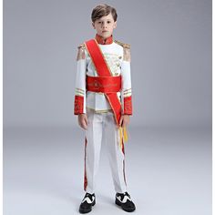 a young boy dressed in a red and white uniform, standing with his hands on his hips