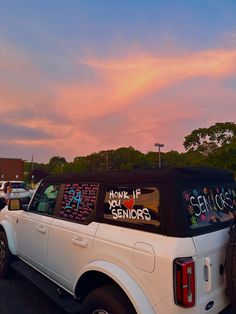 a white truck parked in a parking lot next to other cars with writing on the back