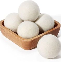 four balls of wool sit in a wooden bowl