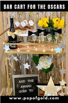 the bar cart for the oscars is decorated with gold and white stars, champagne bottles, and flowers