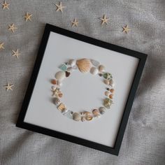 a frame with shells and starfishs in it on top of a sheet of fabric