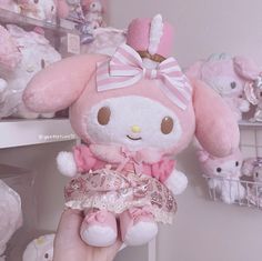 a person holding a pink stuffed animal in front of a shelf full of teddy bears