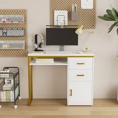 a desk with a computer on it next to a potted plant and other office supplies