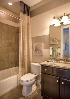 a bathroom with a white toilet sitting next to a bath tub under two light fixtures