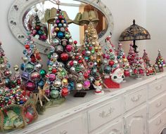 a white dresser topped with lots of christmas ornaments