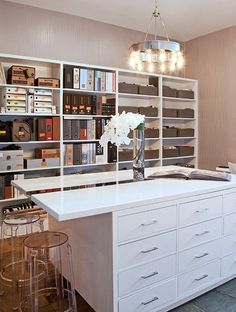 a white kitchen island with lots of drawers and lights hanging from it's ceiling