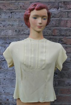 "Rayon blouse  Gorgeous lemon yellow Short-sleeved Mid-20th century -- 1950s or 1960s Intricate panel to front  Deep darts back and front  Shaping padding to shoulders  Cinched-in waist  Very good condition -- tiny hole at back (see photo) -- buttons replaced (see photo) Measurements All round at underarms -- 34\"/87cms Side seam -- 12\"/31cms Sleeve seam -- 1.5\"/4cms Length shoulder to hem -- 20\"/51cms" Fitted Retro Cream Top, Formal Fitted Yellow Blouse, Vintage Short Sleeve Blouse For Vintage Fashion, Vintage Cream Tops For Daywear, Classic Fitted Yellow Top, Classic Yellow Fitted Top, Fitted Classic Yellow Top, Retro Cream Blouse For Daywear, Vintage Cream Short Sleeve Blouse