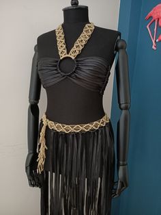 a mannequin wearing a black dress with gold chains and fringes on it