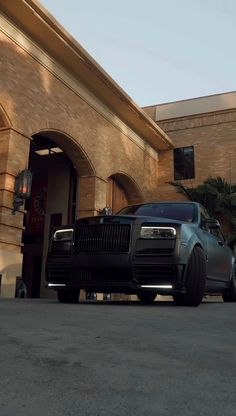 a black rolls royce parked in front of a building