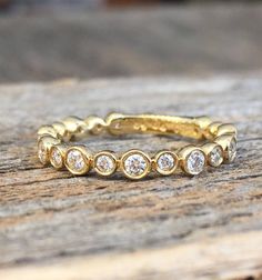 a yellow gold ring with five diamonds on it sitting on top of a piece of wood