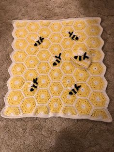 a crocheted yellow and white blanket on the floor with black letters written in it