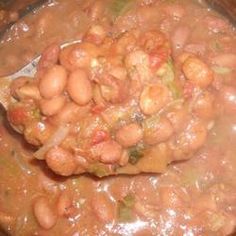 a spoon full of beans and onions in a pot