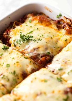 a casserole dish filled with meat and cheese covered in sauce, parsley