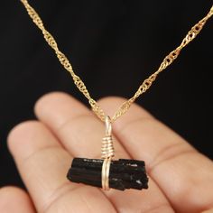 Step into a world of mystical charm with our Enchanted Black Tourmaline Necklace. Each necklace is a testament to nature's wonder, featuring a hand-selected, raw Black Tourmaline stone, celebrated not just for its striking appearance but also for its grounding and protective energies. The pendant, a symbol of elegance and strength, dangles from a high-quality 18-karat gold-filled chain, offering a touch of luxury to your ensemble. This necklace isn't just an accessory; it's a story of the earth' Spiritual Tourmaline Jewelry As A Gift, Spiritual Tourmaline Jewelry Gift, Unique Tourmaline Necklace For Gift, Handmade Tourmaline Artisan Necklace, Black Tourmaline Jewelry As Gift, Black Tourmaline Necklace With Natural Stones, Spiritual Black Necklace With Raw Stone, Black Tourmaline Necklace, Black Tourmaline Stone