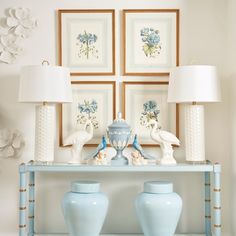 two blue vases sitting on top of a table in front of pictures and lamps