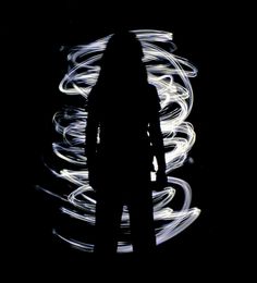 the silhouette of a person standing in front of a black background with white light streaks