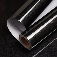 two rolls of black metallic foil sitting on top of a piece of white paper next to each other