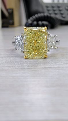 a fancy yellow diamond ring sitting on top of a table