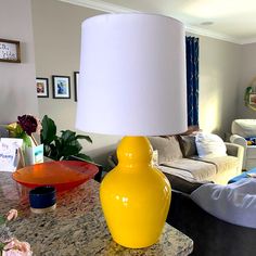 a yellow lamp sitting on top of a table in a living room next to a couch