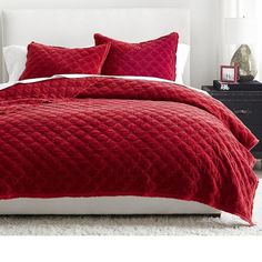 a bed with red comforters and pillows in a bedroom