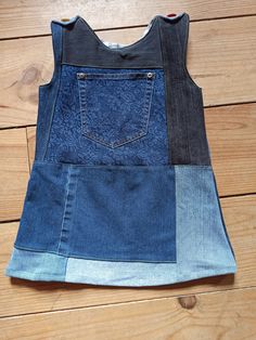 a patchwork denim vest on a wooden floor with the back pocket open and two different colors