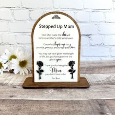 a wooden plaque with a poem written on it and flowers in front of the sign