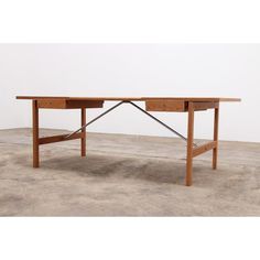 a wooden desk sitting on top of a cement floor next to a white wall in an empty room