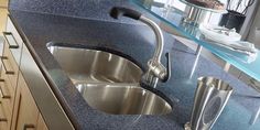 a stainless steel sink and faucet in a blue granite countertop with glass shelves