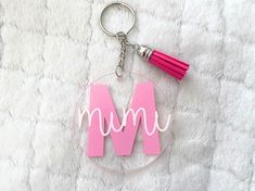 a glass keychain with the letter m on it and a pink tassel