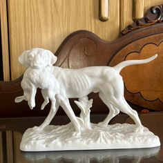 a white dog figurine standing on top of a table next to a mirror