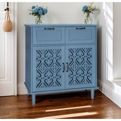 a blue cabinet with two vases on top of it next to a door and window