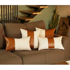 three brown and white pillows sitting on top of a couch next to a stair case