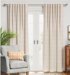 a living room with a chair, rug and white door in front of the window